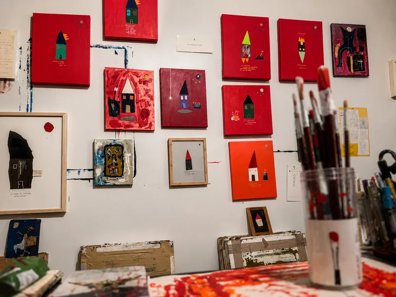 Mur de petits formats rouges au-dessus de la table, pot de pinceaux et flaque de rouge