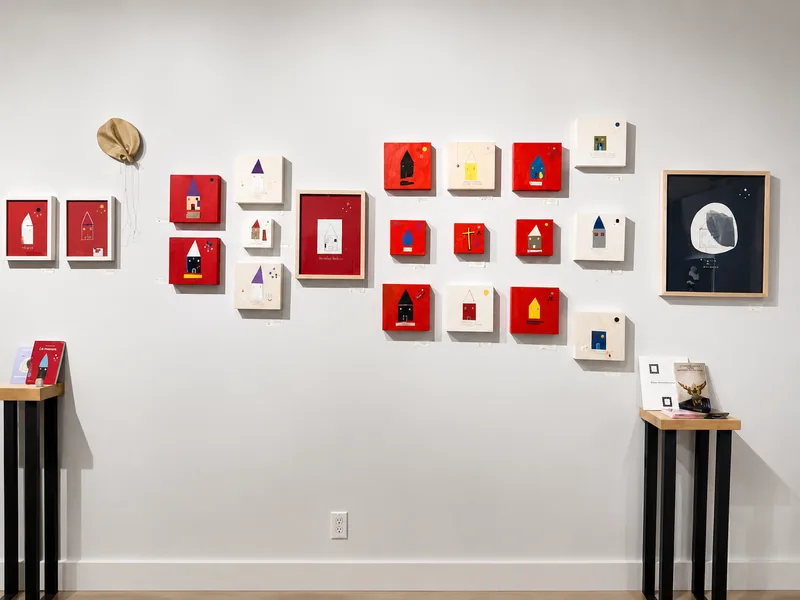 Une vingtaine de petits formats rouges et crème alignés sur un mur blanc